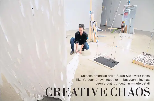  ??  ?? Sarah Sze adjusts dried strips of paint
that hang to the floor at the Tanya Bonakdar Gallery in
New York.