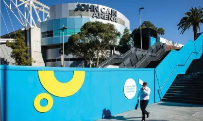  ?? Photograph: Diego Fedele/EPA ?? A man walks by an Australian Open sign at Melbourne Park. Ticket sales will be limited for theyear’s opening grand slam due to a surge in Omicron cases.