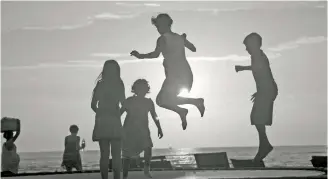  ??  ?? Children leaping with joy in a beach in Goa