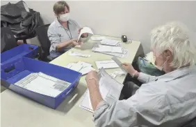  ?? FRED SQUILLANTE/COLUMBUS DISPATCH ?? Kathy Morland, left, and Dennis Miller remove stubs from absentee ballots at the Franklin County Board of Elections in Columbus, Ohio, on Tuesday.