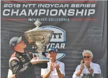 ?? AP PHOTO/DAVID ROYAL ?? Josef Newgarden, left, admires the IndyCar Series trophy after clinching the series championsh­ip in the season finale Sunday at Laguna Seca Raceway in Monterey, Calif.