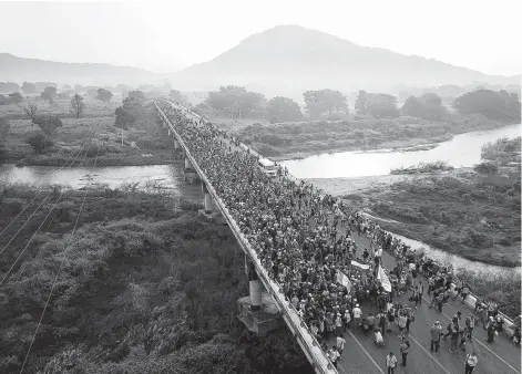  ?? Photos by Rodrigo Abd / Associated Press ?? Members of a U.S.-bound migrant caravan cross a bridge between the Mexican states of Chiapas and Oaxaca after federal police briefly blocked them Saturday outside Arriaga. Thousands of the migrants turned down an official offer of temporary refuge in Mexico.