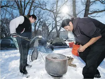  ?? TROY FLEECE ?? James Dubois, left, and Prescott Demas start a fire at the camp in February.