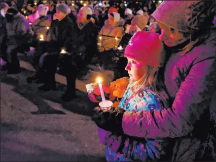  ?? Jeffrey Phelps The Associated Press ?? A child takes part in a candleligh­t vigil in downtown Waukesha, Wis., after an SUV plowed into a Sunday Christmas parade, killing multiple people and injuring dozens.