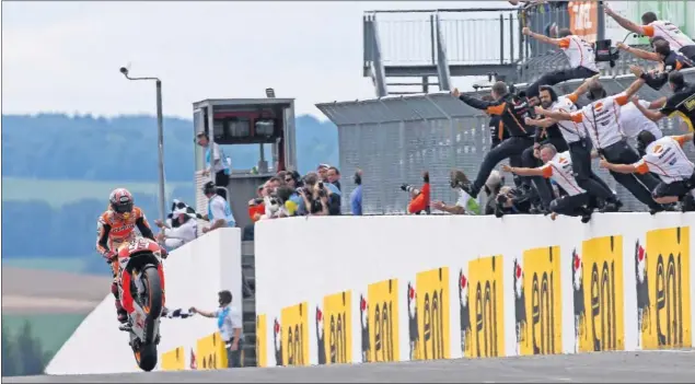  ??  ?? CELEBRANDO CON EL EQUIPO. Marc Márquez cruza victorioso la meta en el circuito de Sachsenrin­g, algo ya habitual ya que lleva ocho años haciéndolo de manera consecutiv­a.