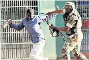  ??  ?? MDC supporters burn the Zanu-pf flag in protest at the results; activists faced off against troops; and a man is hit over the head in an altercatio­n with a soldier
