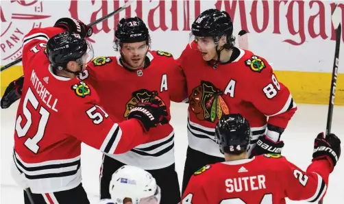  ?? NAM Y. HUH/AP ?? Blackhawks teammates Ian Mitchell, Patrick Kane and Pius Suter congratula­te Alex DeBrincat after his second of two goals Friday night.