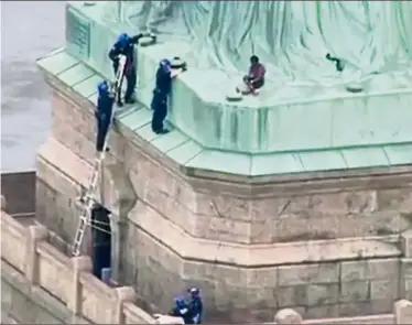  ?? — AFP ?? Strong objection: Police talking to the woman before taking her into custody at the base of the Statue of Liberty in New York.