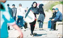  ?? (AFP) ?? Meriem walks along the coastline after a surf session in Rabat.