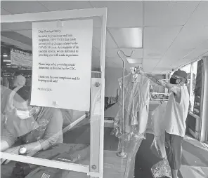  ?? RICK WOOD/ USA TODAY NETWORK ?? Oscar Marin, owner of Prestige Dry Cleaners in Milwaukee, fills an order while Star Carter, a customer for 15 years, picks up his order. Still, business “isn’t back to normal by any means,” Marin says.