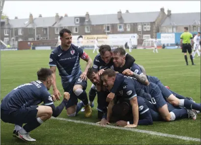  ??  ?? Gozie Ugwu is mobbed by team-mates after scoring the crucial second goal for Raith Rovers