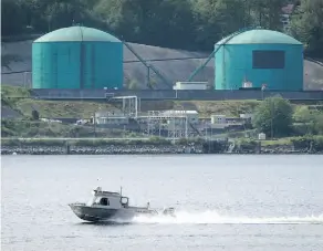  ??  ?? A fishing boat in North Vancouver passes the Kinder Morgan Burnaby Terminal in Burnaby, B.C. Lawyers for the Tsleil-Waututh Nation are asking the Federal Court of Appeal to stop the National Energy Board’s review of the Trans Mountain pipeline expansion.