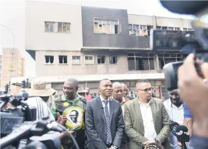  ?? Picture: Nigel Sibanda ?? GRIM. Joburg mayor Kabelo Gwamanda, centre, at a media briefing outside the gutted Express building in the city yesterday. City manager Floyd Brink is on the right.