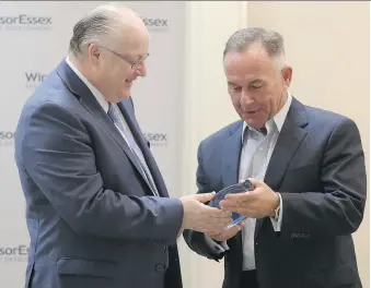  ?? JASON KRYK ?? Windsor Essex Economic Developmen­t Corp. CEO Stephen MacKenzie, left, presents retiring corporatio­n board chairman Marty Komsa with a plaque on Tuesday during the annual general meeting.