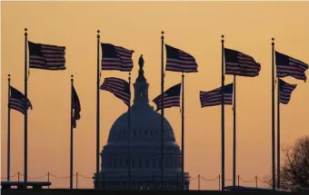 ?? AP PHOTOS ?? SET TO BEGIN: Flags blow in the wind in front of the Capitol, where senators, above right, were sworn in Thursday for the impeachmen­t trial that gets under way today.