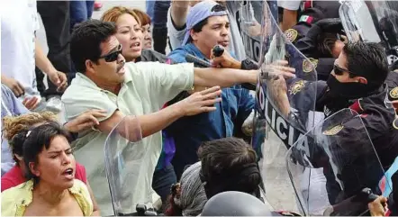  ??  ?? Fists of fury: Relatives of inmates clashing with riot policemen outside Apodaca prison in Mexico where at least 44 inmates were killed yesterday. — Xinhua