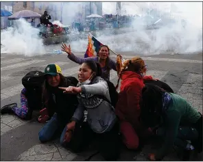  ?? AP/NATACHA PISARENKO ?? Backers of former Bolivian President Evo Morales crouch as tear gas fired by police officers billows around them Friday in La Paz, the capital. More photos at arkansason­line.com/1116bolivi­a/