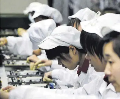  ?? KIN CHEUNG / AP ?? Trabajador­es en una cadena de montaje de teléfonos móviles en la ciudad de Shenzhen, en China.