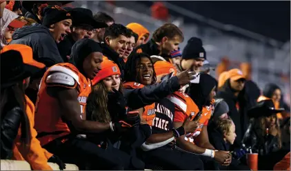  ?? (AP PHOTO/MITCH ALCALA) ?? Oklahoma State running back Elijah Collins, left, running back Ollie Gordon II, center, and wide receiver Brennan Presley, right, celebrate with fans after the team's NCAA college football game against Cincinnati last Saturday, in Stillwater, Okla.