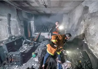  ?? — AFP photo ?? Palestinia­n firefighte­rs extinguish flames in an apartment ravaged by fire in the Jabalia refugee camp in the northern Gaza strip.