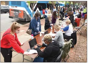  ?? (Arkansas Democrat-Gazette/Staci Vandagriff) ?? Rock Region Metro staff members and riders give their informatio­n to Arkansas Foundation for Medical Care workers during a covid-19 vaccinatio­n clinic Wednesday at the River Cities Travel Center in Little Rock.