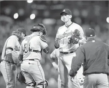  ?? D. Ross Cameron Associated Press ?? THE HOOK is coming and Brandon McCarthy knows it as he, Justin Turner (10) and catcher Carlos Ruiz wait for Dodgers Manager Dave Roberts, right. McCarthy faced six batters, retiring none, and all six scored.