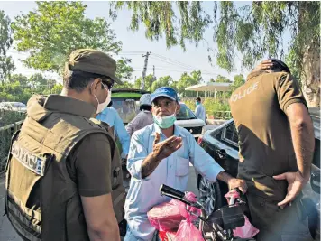  ??  ?? Police monitor and redirect people at a checkpoint for a sealed-off area in Rawalpindi in order to contain a high infection area