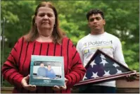  ?? The Associated Press ?? UNTOLD NUMBERS: Florence Hopp, left, holds a photograph of herself and her husband Robert Hopp during a cruise in 2017, as her son J.J. Brania-Hopp holds the American flag the military presented to them in April after his father’s death, on Friday at their home in Boonton, N.J.