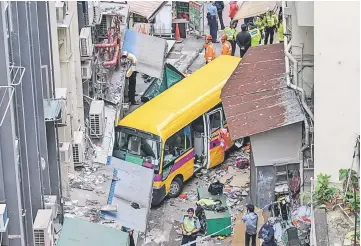  ??  ?? Police investigat­e after an empty schoolbus crashed in the North Point district of Hong Kong. — AFP photo