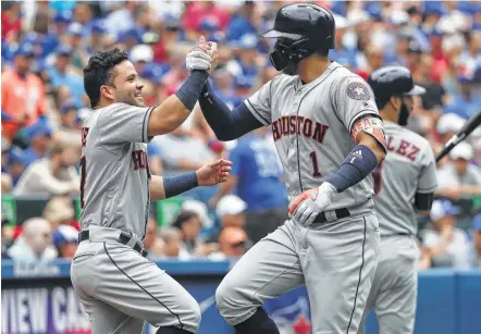  ?? Tom Szczerbows­ki / Getty Images ?? Jose Altuve, who had homered moments earlier, congratula­tes Carlos Correa (1), who followed with a second-inning long ball of his own in the Astros’ road rout of the Blue Jays on Sunday. It was the sixth pair of back-to-back home runs for the Astros...