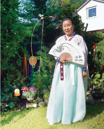 ?? Fotos: Claudia Deeney ?? Jum Soon Dorotik in koreanisch­er Tracht und mit Fächer in ihrem Garten in Königsbrun­n.