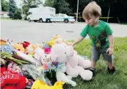  ?? JOHN WOODS/THE CANADIAN PRESS ?? A toddler places a stuffed toy on a memorial for Anna, 2, and three-month-old Nicholas, who were killed by their mother Lisa Gibson in Winnipeg this past July.