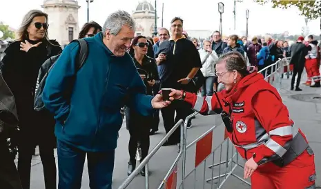  ?? Foto: Petr Topič, MAFRA ?? Členka Červeného kříže rozdává lidem teplé nápoje. V noci a po ránu byla u řeky zima a fanoušci Karla Gotta byli promrzlí – to je však ani v nejmenším neodradilo. Ještě před otevřením paláce Žofín už jich tam čekalo několik set.