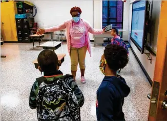  ?? PHOTOS BY STEVE SCHAEFER FOR THE ATLANTA JOURNAL-CONSTITUTI­ON ?? Jackson Elementary teacher Darlene Williams greets her students as they return for in-person learning Monday at the Jonesboro school.