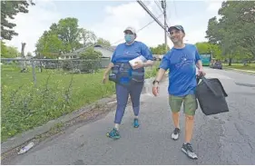  ?? STAFF PHOTO BY MATT HAMILTON ?? Nurse Allessandr­a Vitrano and Dr. Matthew Kodsi walk through a neighborho­od near East Lake Park in Chattanoog­a on Saturday. The two went door to door to inform residents of a block party going on in the park that offered the COVID-19 vaccines.