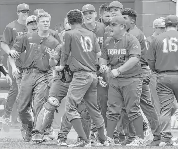  ?? Jerry Baker photos ?? Travis’ Jaren Burks (10) is the center of attention after hitting an RBI single and later scoring in a seven-run sixth inning that lifted Travis to an 8-2 win over Katy in the third game of their Class 6A regional quarterfin­al series.