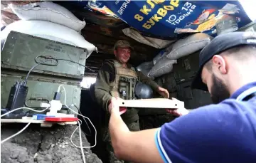  ?? — AFP photos ?? Aleksey Kachko, co-owner of the small pizzeria “Pizza Veterano” in Mariupol, hands out pizza to Ukrainian servicemen at the frontline with Russian-backed separatist­s.