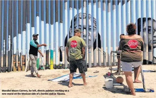  ?? ELLIOT SPAGAT/AP ?? Muralist Mauro Carrera, far left, directs painters working on a new mural on the Mexican side of a border wall in Tijuana.