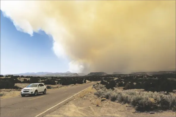  ?? ROBERT BROWMAN/AP ?? A VEHICLE HEADS AWAY FROM A PLUME OF SMOKE from the Cerro Pelado Fire burning in the Jemez Mountains on Friday in Cochiti, N.M..