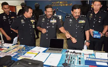  ??  ?? Major bust: Comm Thaiveegan (centre) and ACP Anuar (second from right) showing the luxury items seized from the burglary syndicate at the state police contingent headquarte­rs.