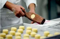  ??  ?? Chef Yip Wing-wah uses a heavy wooden holder containing a dough ball as he makes “spring moon mini egg custard mooncakes” at Hong Kong’s famous colonial era Peninsula Hotel. —