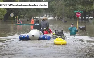  ??  ?? A RESCUE PARTY searches a flooded neighborho­od in Houston.