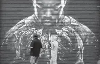  ?? CHRIS PIZZELLO/ASSOCIATED PRESS FILE ?? Pedestrian­s look up at a mural by artist Shane Grammer of late actor Chadwick Boseman’s character T’Challa from the 2018 film“Black Panther,” on Sept. 8 in Los Angeles. Boseman died of colon cancer on Aug. 28 at age 43, an illness he kept secret from almost everyone, making movies in between surgeries and treatments.