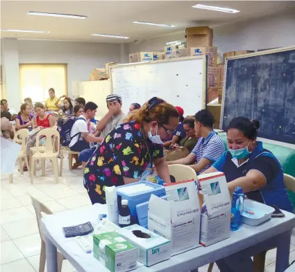  ?? SUNSTAR FOTO / ALAN TANGCAWAN ?? Health officials of the Mandaue City Government attend to residents who were bitten by a rabid dog. City officials advised the public to report to authoritie­s if there’s a rabid dog in their area.