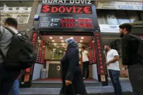  ?? BURHAN OZBILICI — THE ASSOCIATED PRESS ?? People walk past a currency exchange shop in Istanbul, Tuesday.