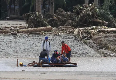  ?? Reuters ?? Survivors of the floods and landslides travel on a makeshift raft after a bridge was destroyed in Salvador, Lanao del Norte