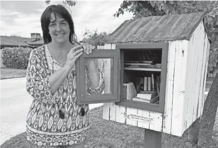  ?? MICHELLE A. MONROE/AP ?? Kerri Kaplan, a fifth grade teacher, stands next to a small library she has in her front yard in Phoenix, Ariz., on April 17.