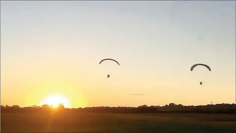  ?? COURTESY PHOTOS ?? A beautiful sunset is in the background for these two paraglider­s. Capt. Jeff O’Brien of Prairie Grove Police Department is on the left and his trainer, Britton Shaw of Fort Smith, is on the right.