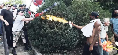  ?? AP PHOTO ?? A counter-demonstrat­or uses a lighted spray can against a white nationalis­t demonstrat­or at the entrance to Lee Park in Charlottes­ville, Virginia, on Saturday, August 12.