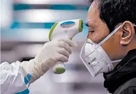  ?? HECTOR RETAMAL/GETTY-AFP ?? A medical staffer takes the temperatur­e of a man Saturday at the Wuhan Red Cross Hospital in Wuhan, China.